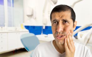 Distressed man holding his cheek in pain