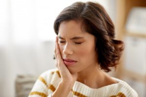 Woman in striped sweater nursing a toothache